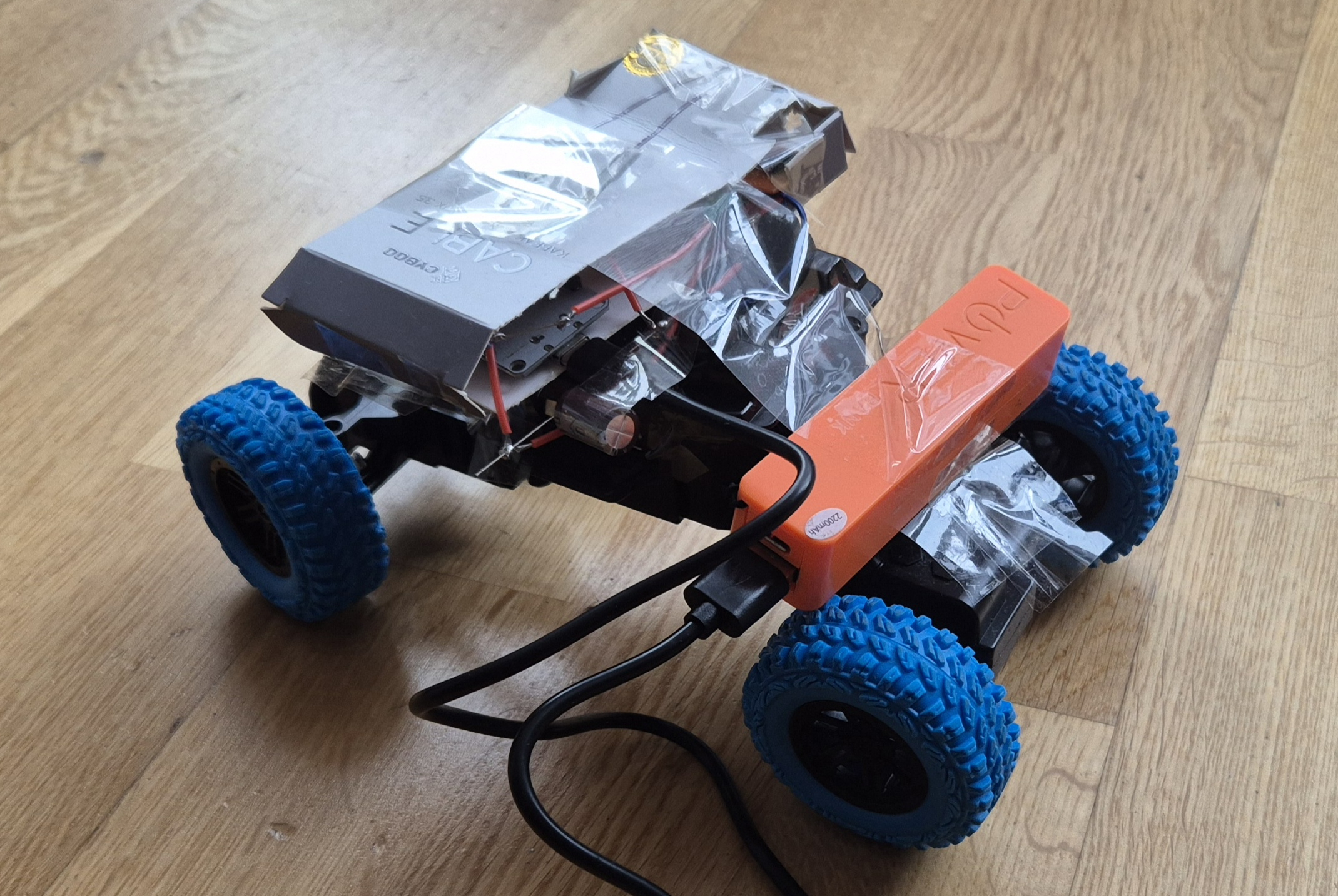 Picture of a small RC car with several cardboard boxes glued onto it